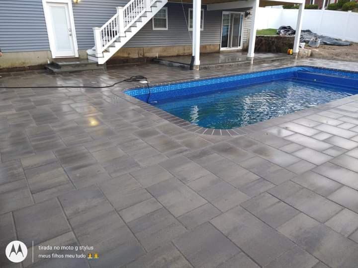 Custom pool deck in dark gray pavers around an in-ground pool