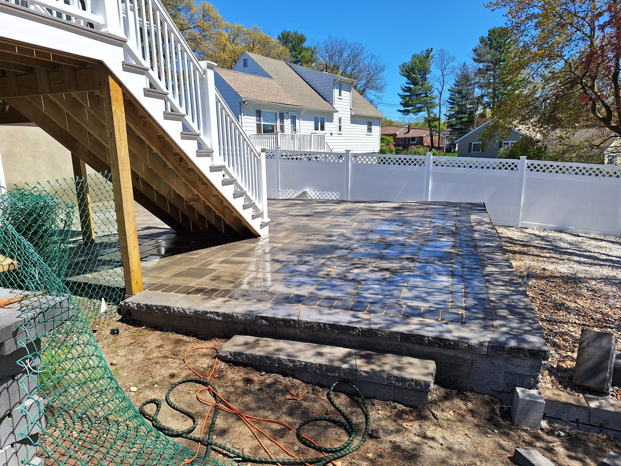 Elevated paver patio with retaining-block base behind a deck